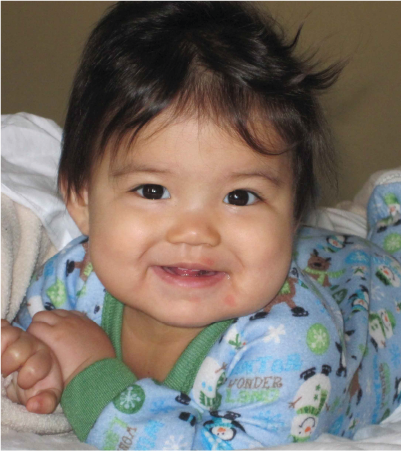 Smiling infant laying on a bed